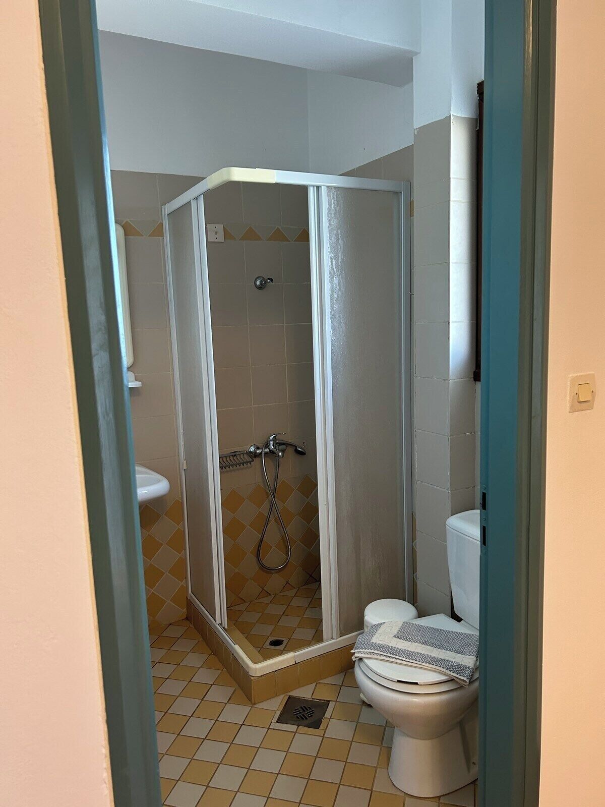 Un baño pequeño con cabina de ducha, inodoro y lavamanos.