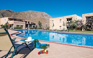 A swimming pool with lounge chairs and a mountain backdrop. - Areti Hotel (Chania)
