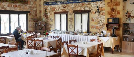 A restaurant with stone walls, multiple tables, and chairs.
