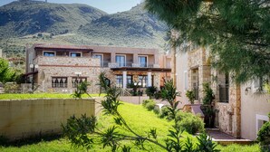 A two-story building with stone and plaster exterior, a balcony, and a view of a mountainous landscape. - Areti Hotel (Chania)