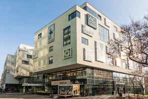 Un hotel moderno con fachada de vidrio, una terraza en la azotea y un letrero que dice 'Panta Rhei'.