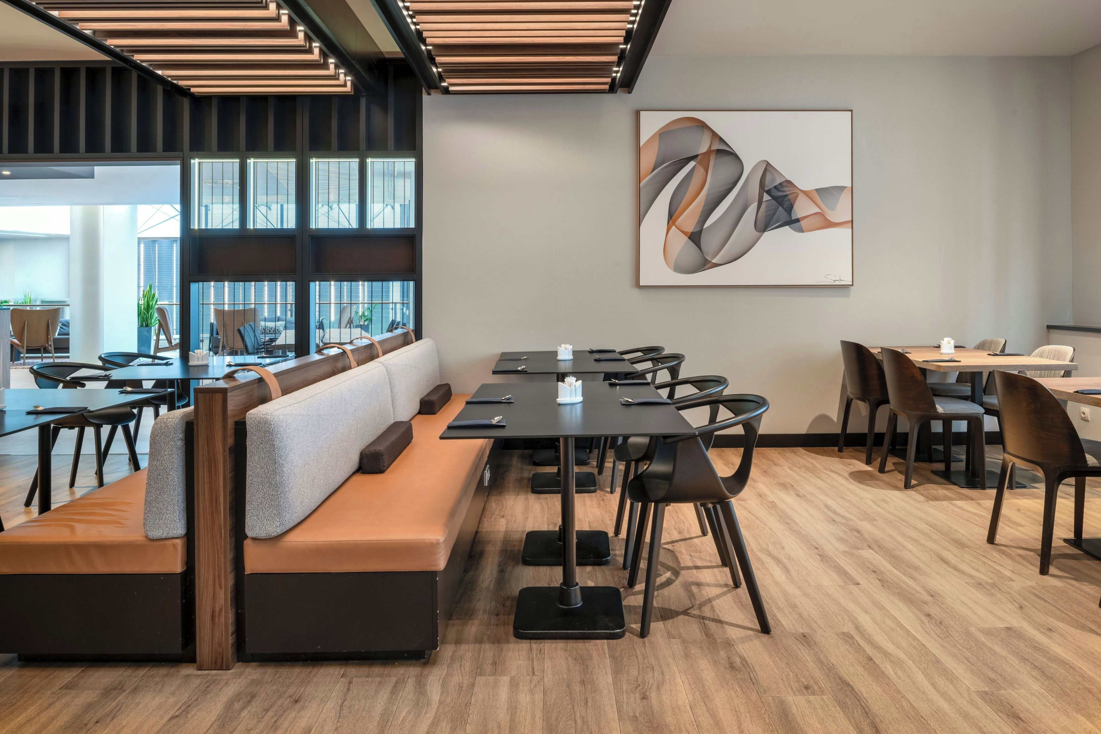 Un espace de bureau moderne avec une longue table, plusieurs chaises, un canapé et un grand tableau abstrait accroché au mur.