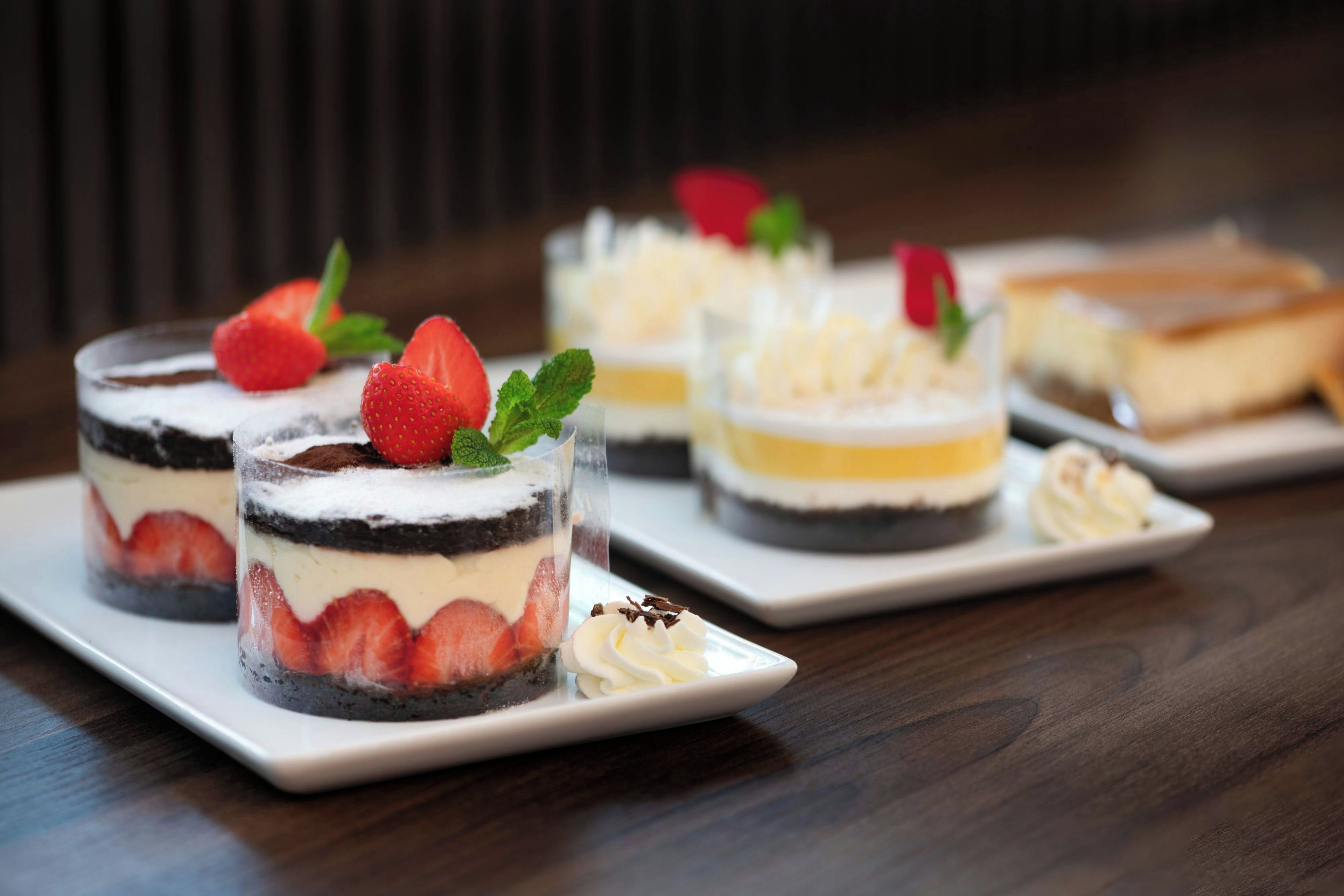 Une présentation de desserts avec des gâteaux à plusieurs couches et des fraises, le tout disposé sur une assiette blanche.