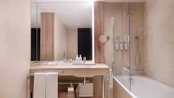 A modern bathroom with a large mirror, two sinks, a shower, and a bathtub.