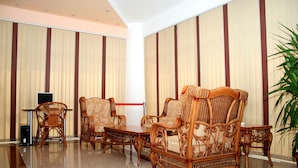 A room with a polished floor, a large potted plant, and a seating area with wicker furniture. - Denisa Hotel Otopeni (Otopeni)