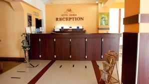 A reception desk at Hotel Denisa with a wooden finish, a clock, and a sign indicating wheelchair accessibility. - Denisa Hotel Otopeni (Otopeni)