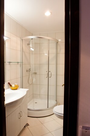 A modern bathroom with a glass-enclosed shower, a white toilet, and a white sink with a glass bowl.