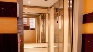 An elevator interior with a control panel, emergency stop button, and a sign with instructions. - Denisa Hotel Otopeni (Otopeni)