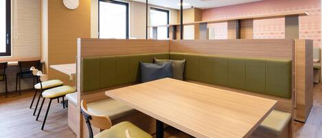 Un comedor moderno con una mesa de madera, asientos tapizados en tono verde y sillas amarillas.