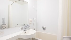 Une salle de bain moderne avec un lavabo blanc, un miroir et une baignoire. On y trouve des distributeurs de savon liquide et un porte-serviettes.