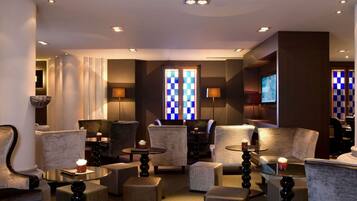 A modern hotel lobby with plush seating, a checkered window, and ambient lighting.