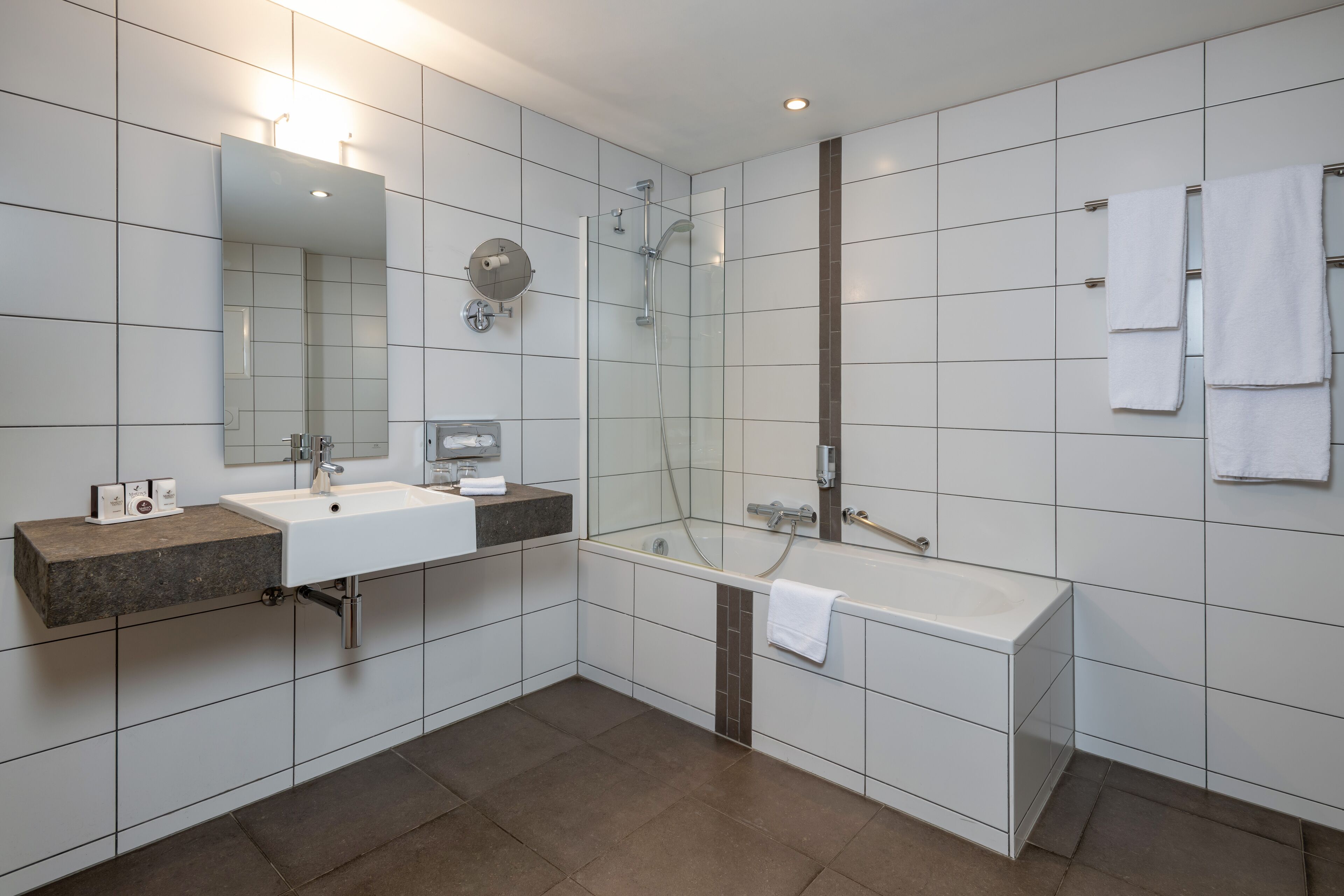 A modern bathroom with a large mirror, a sink, a bathtub, and a shower.