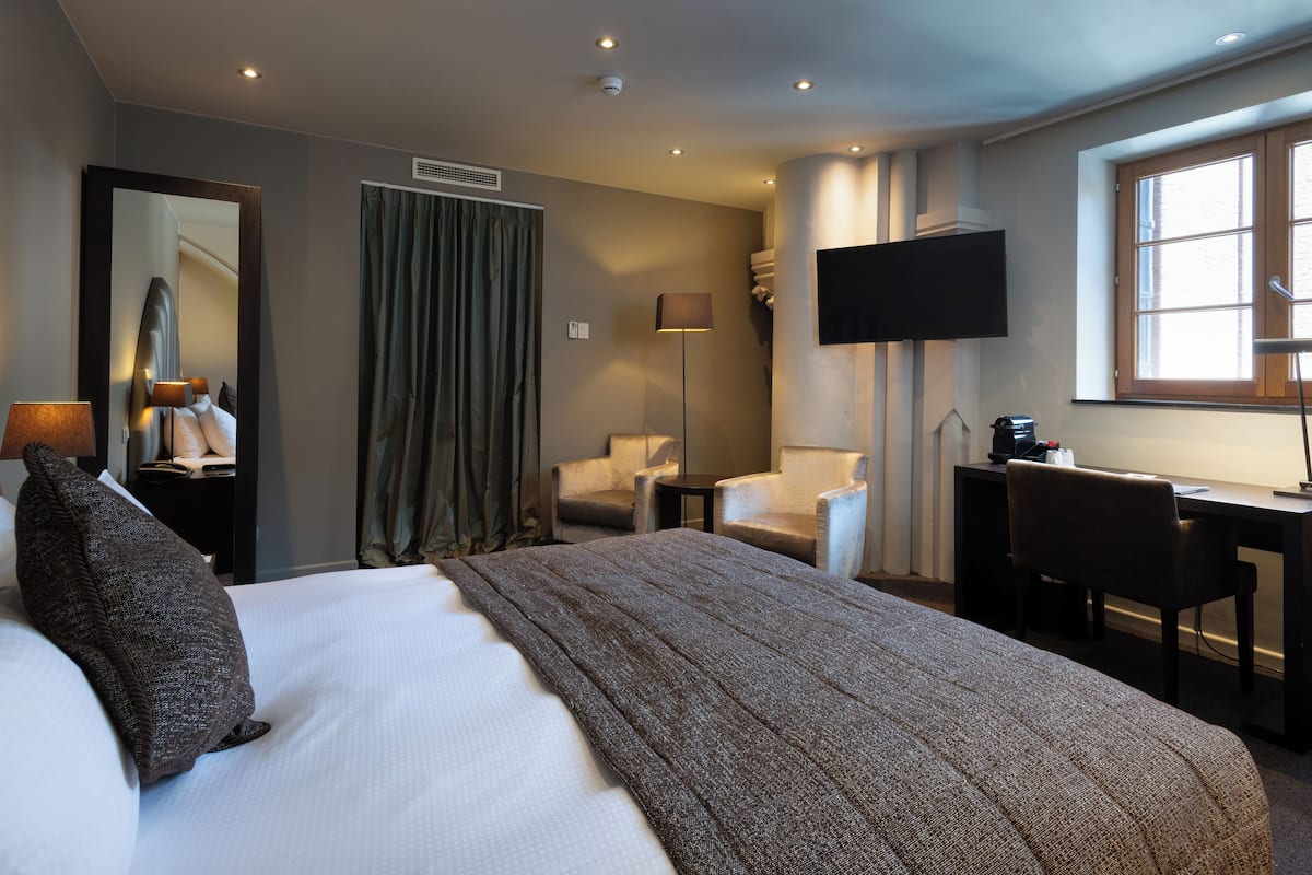 Una habitación de hotel con una cama grande, un escritorio, una silla, un televisor y una ventana.