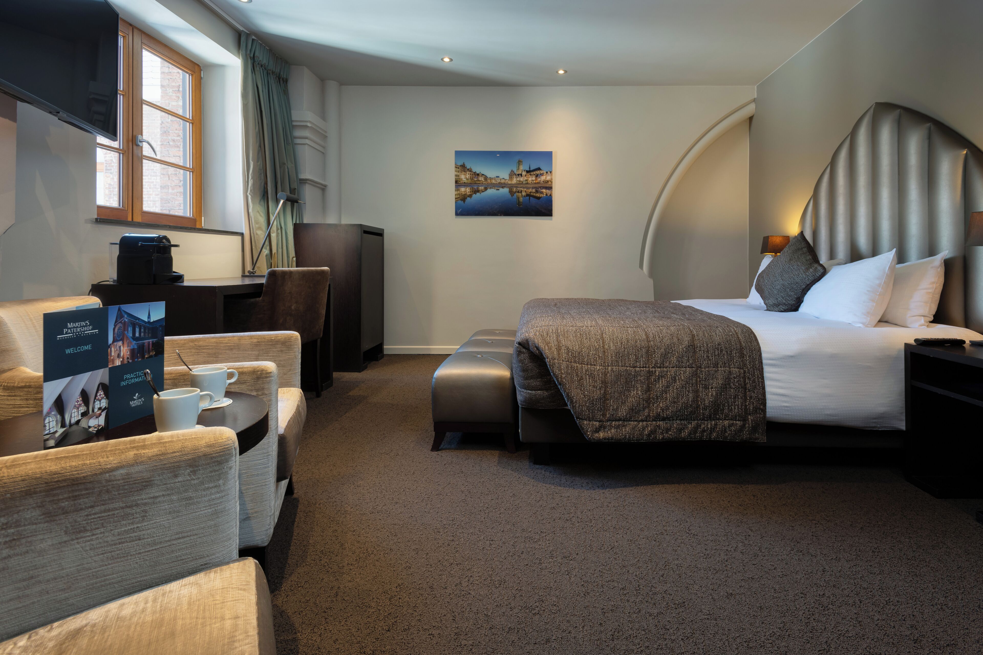 A hotel room with a bed, a desk with a computer, a chair, and a coffee table.