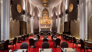 Un restaurante con alfombra roja, varias mesas y sillas dispuestas en un espacio largo y estrecho.