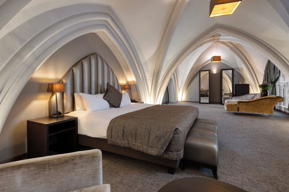 Una habitación de hotel moderna con una cama grande, un área de descanso y vistas a la ciudad.