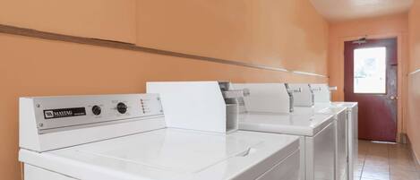 Une buanderie équipée de deux lave-linge et deux sèche-linge Maytag, d’une plinthe en bois et d’une porte donnant sur un espace extérieur.
