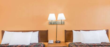 Une chambre d’hôtel avec deux lits, chacun agrémenté d’une literie à motifs, une table de chevet avec une lampe et un téléphone fixé au mur.