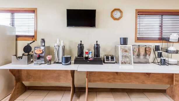 Eine Küche mit einem Waffeleisen, einer Kaffeemaschine, einem Toaster und einem Fernseher an der Wand.