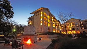 Un edificio de varios pisos con fachada de piedra, zona de estar al aire libre y chimenea.