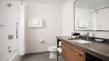 A modern bathroom with a bathtub, toilet, and vanity with a mirror.