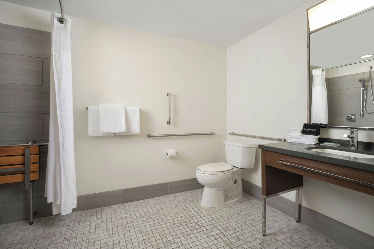 Un baño moderno con inodoro, lavamanos, ducha y un banco de madera.