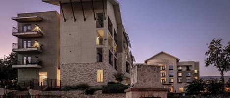 A multi-story building with balconies, a stone facade, and a central courtyard with a fireplace.