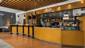 Zona de bar moderna con techo de madera, un cartel con la carta y una barra con diversas bebidas.
