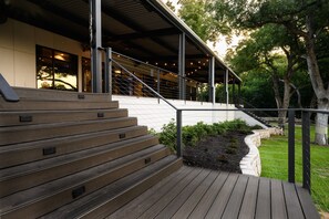 A wooden staircase leading to a covered outdoor area with a railing, surrounded by greenery and trees. - Courtyard by Marriott New Braunfels River Village (New Braunfels)