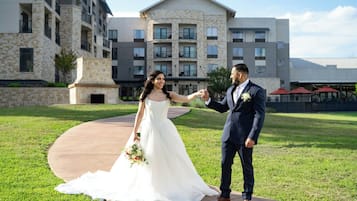 Una pareja tomándose de las manos en un camino de concreto con un edificio al fondo.