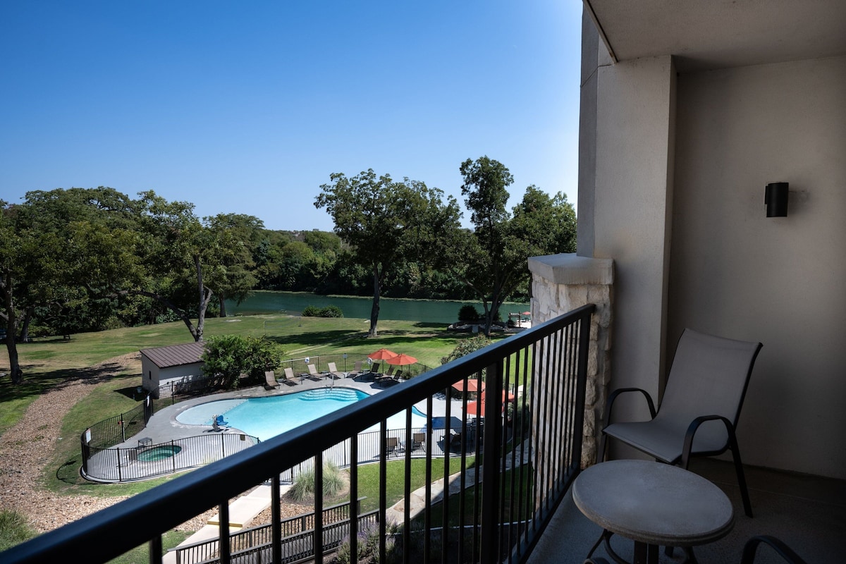 Un balcón con vistas a una piscina, un césped y un edificio pequeño.