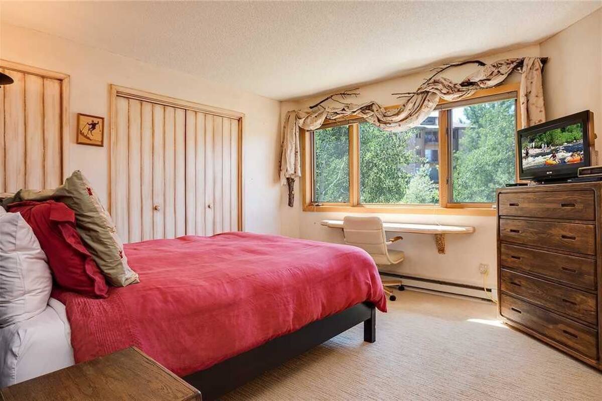 Une chambre à coucher comprenant un lit, un bureau, une chaise, une commode et un téléviseur.