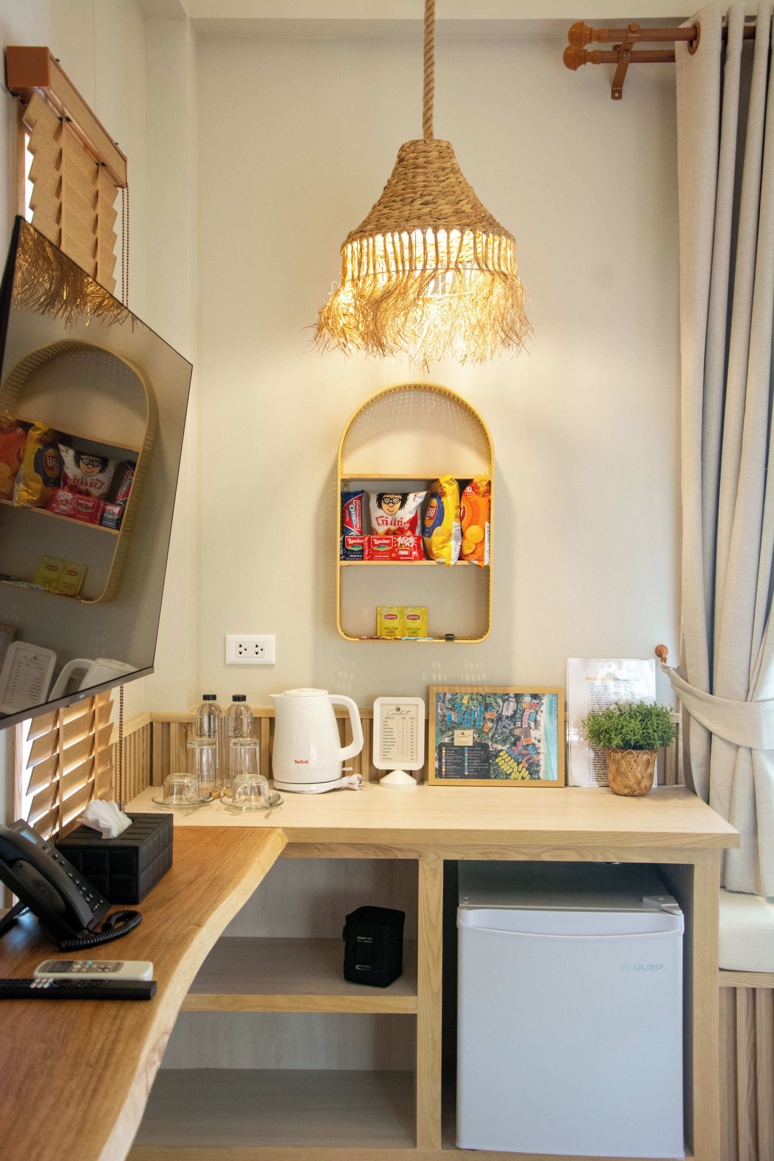 Una cuina compacta amb nevera, cafetera i una petita prestatgeria amb aperitius.