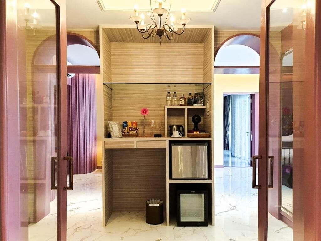 A modern interior with a built-in kitchen area, a chandelier, and a glass partition.