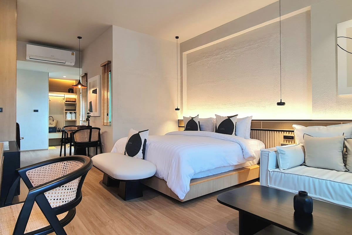 A modern hotel room with a bed, a sofa, a desk, and a chair.