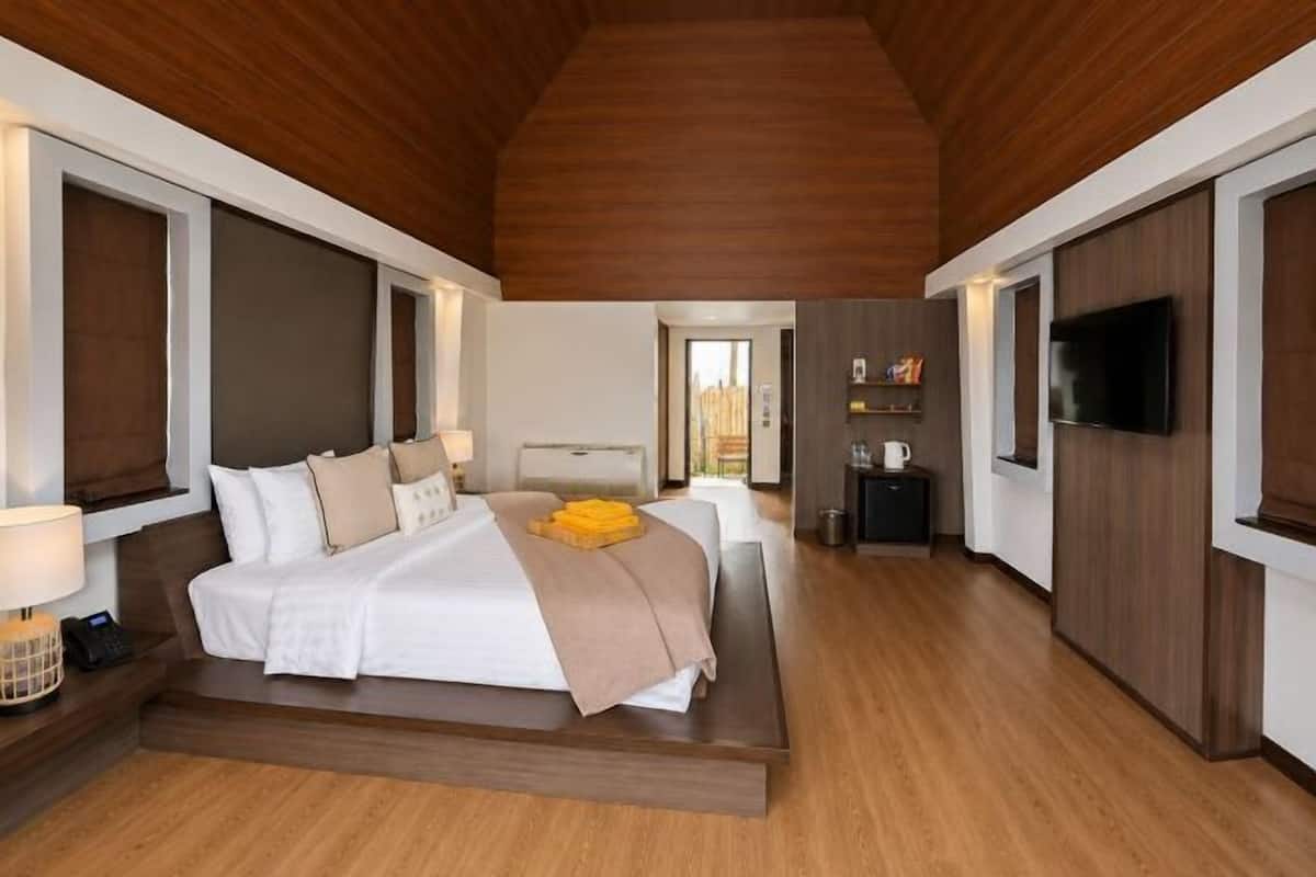 A modern hotel room with a large bed, bedside tables, a TV, and a view of the outdoors.