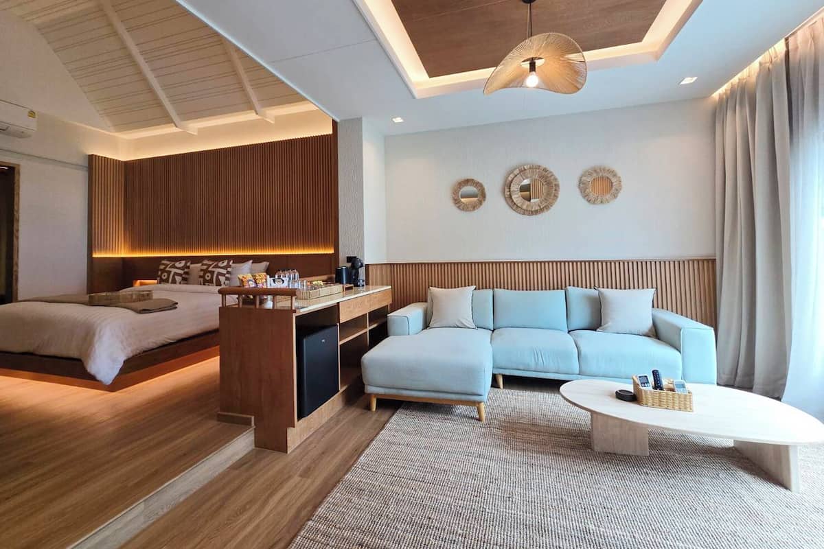 A modern hotel room with a bed, a sofa, a desk, and a coffee table.
