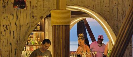 A bar area with wooden walls and a view of the ocean.