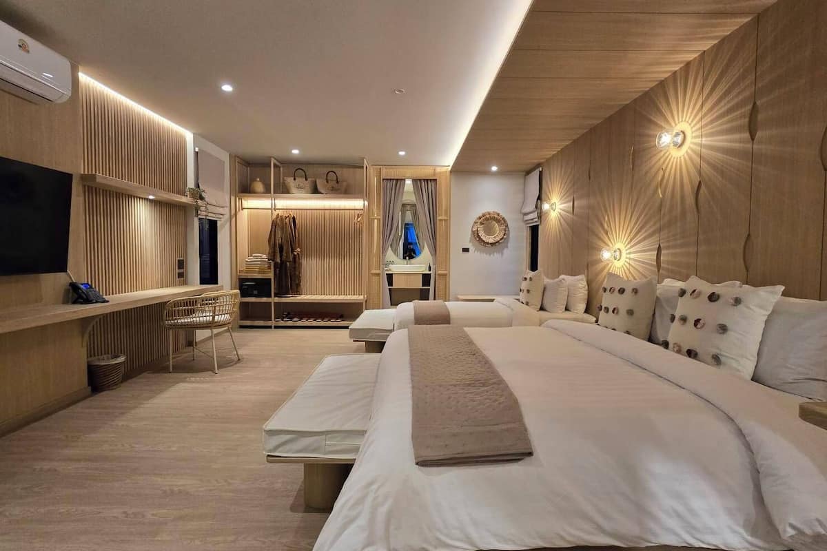 A modern hotel room with a large bed, a seating area with a TV, and a walk-in closet.
