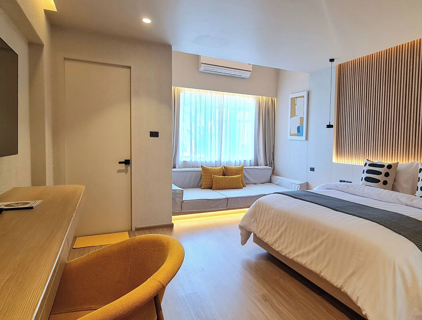Una habitación de hotel moderna con cama, sofá, escritorio y ventana con cortinas.