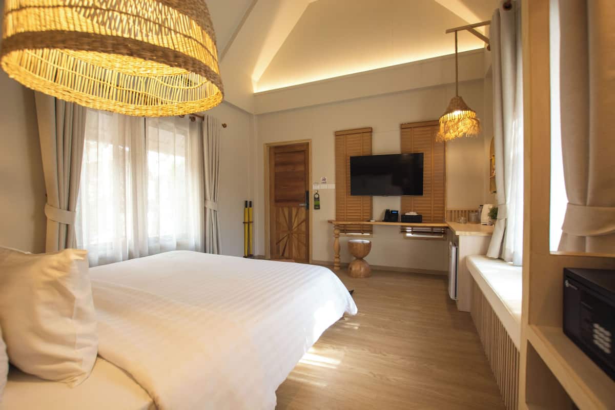 A hotel room with a large bed, a television, a kitchenette, and a dining area.