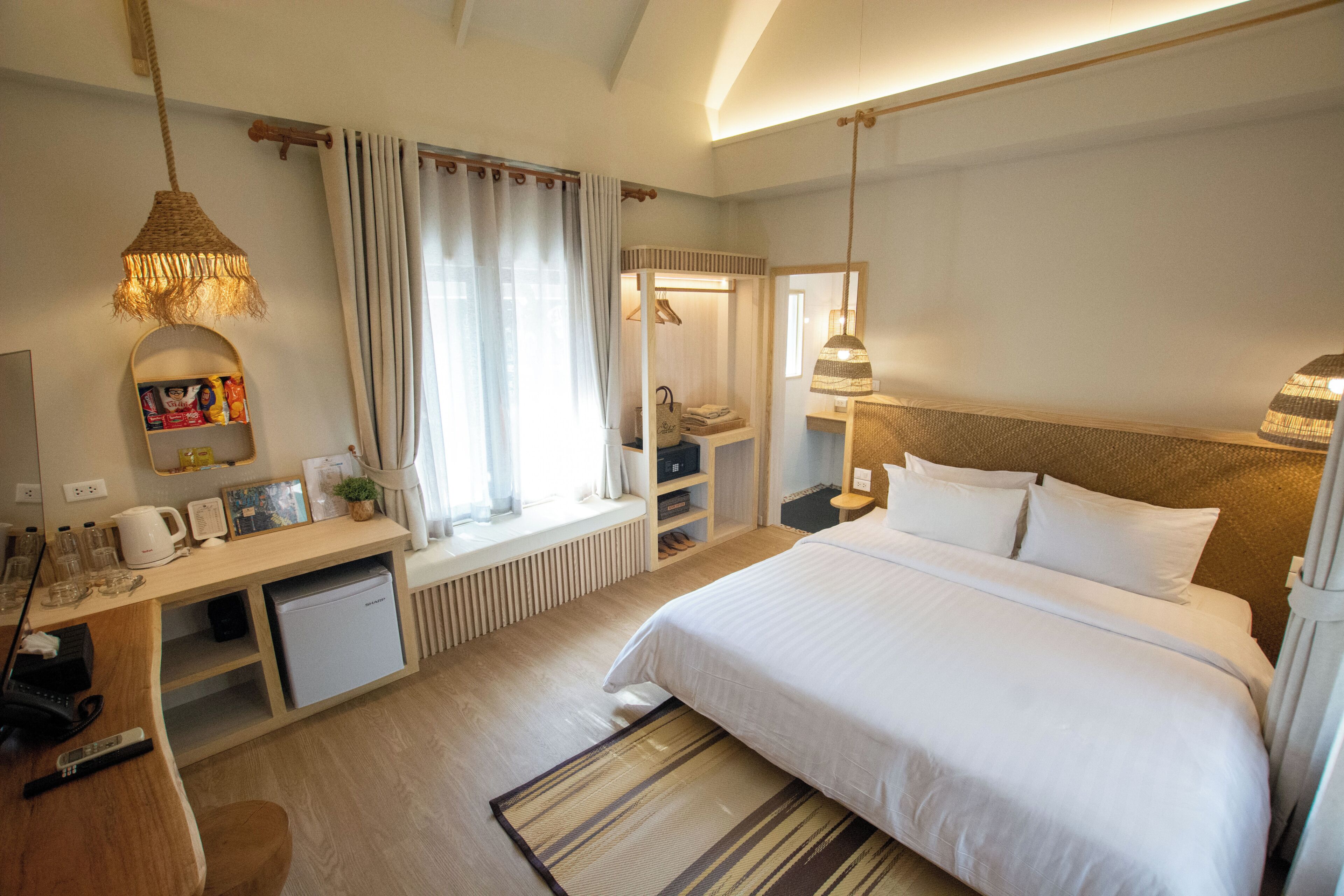 A hotel room with a bed, desk, and a small kitchenette.
