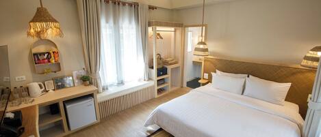 A hotel room with a bed, desk, and a small kitchenette.