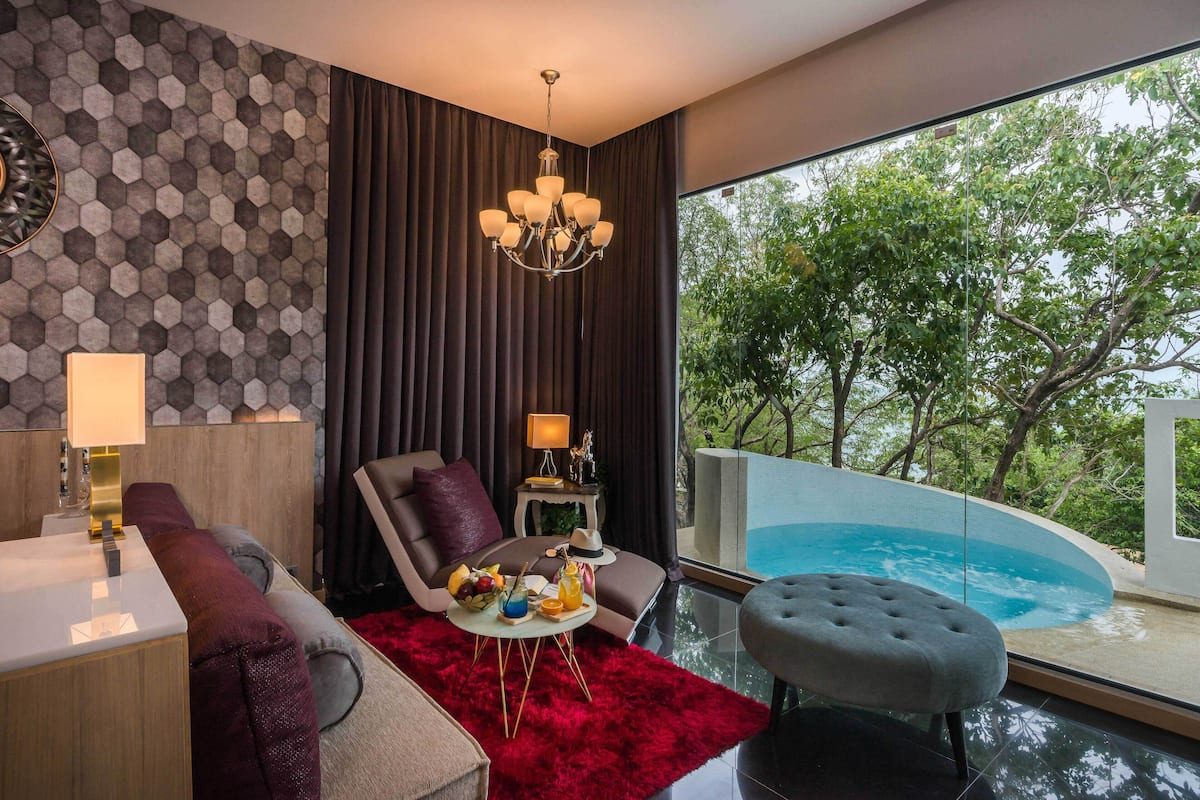 A modern living room with a view of a swimming pool, a chandelier, and a red rug.