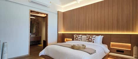 Un dormitorio moderno con una cama grande, panel de pared de madera e iluminación integrada.