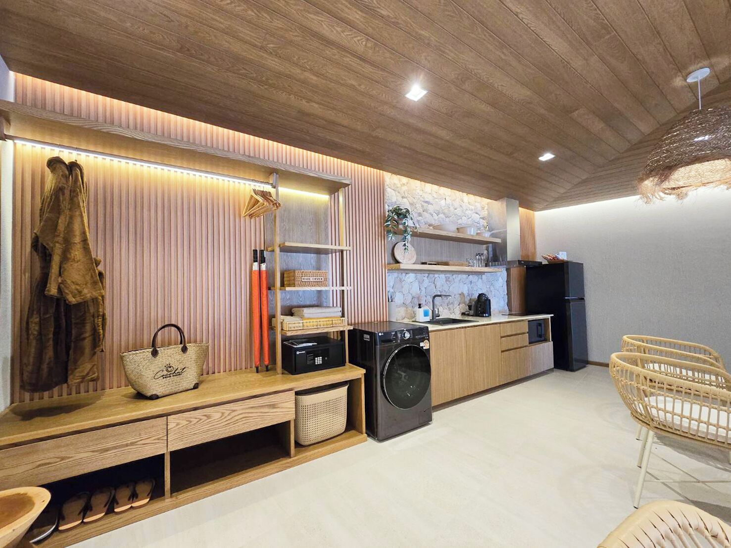 A modern kitchen with wooden cabinetry, a built-in washing machine, and a bench with storage.