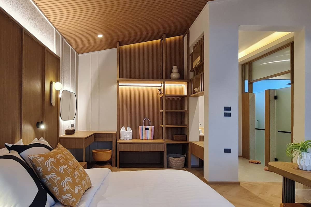 A modern bedroom with a large bed, wooden headboard, built-in shelving, and a bedside table.