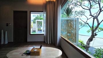 A hotel room with a round table, a wicker basket, and a view of a tree and a stone wall.