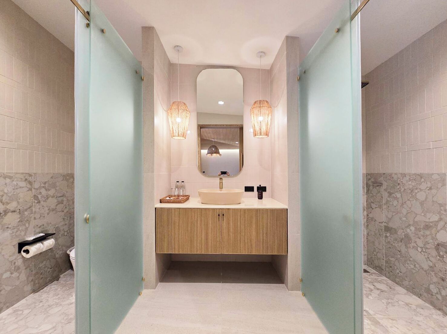 A modern bathroom with a freestanding sink, a mirror above it, and two wall-mounted lights.