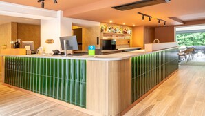 Een moderne bar met een toonbank, barstoelen en een groot raam met uitzicht op het buitengebied.